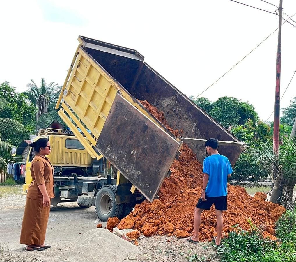 Kepala Sekolah SD Negeri 118194 Romauli Samosir menerima bantuan tanah timbunan dari Kasat Narkoba Polres Labuhan Batu AKP Hardiyanto di halaman sekolah