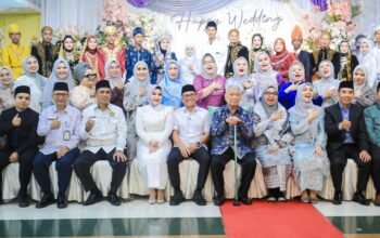 Zakiyuddin Harahap menyerahkan buku nikah kepada pasangan pengantin dalam nikah massal di Medan